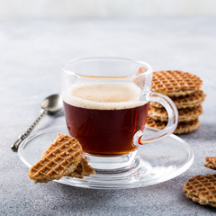 Glass cups of coffee with mini stroopwafel, syrupwaffles cookies on light gray background with copy space.
