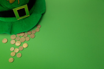 Happy St Patricks Day leprechaun hat with gold coins on green background. Top view