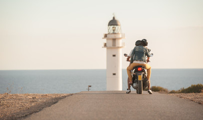 couple ride a bike by the lighthouse - obrazy, fototapety, plakaty