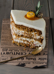 piece of carrot cake on fragment of newspaper on wooden background