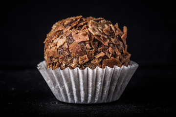 One chocolate candy on a slate background. Toned