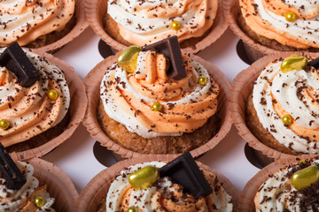 Vanilla cupcakes with orange and white creamcheese and chocolate decor. Selective focus. Shallow depth of field