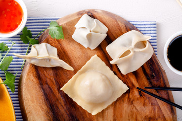 Assorted dumpling set with sauces on wooden cutting board