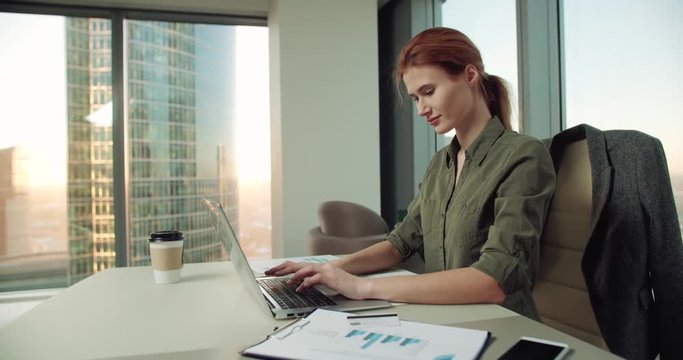 4k young business woman in modern office uses a laptop for video, dolly shot