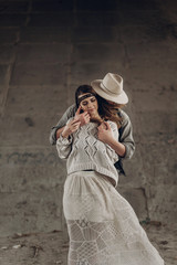 Handsome cowboy man in white hat touching cheek of beautiful boho gypsy woman with leather headband, posing outdoors