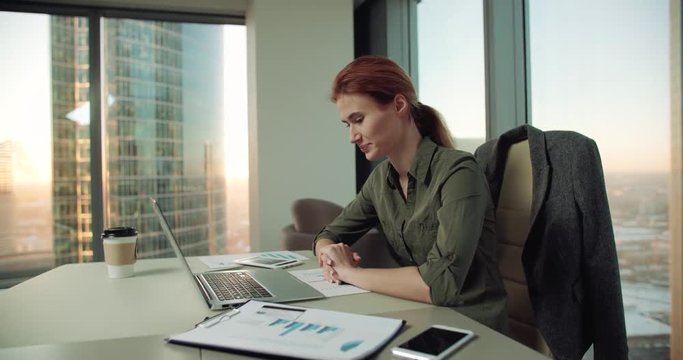 4k young business woman in modern office uses a laptop for video, dolly shot