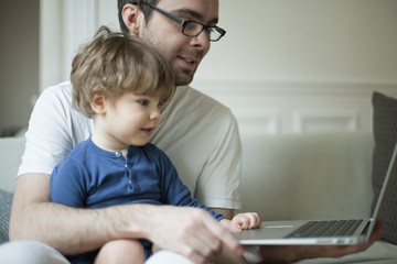 Toddler boy using laptop computer with father