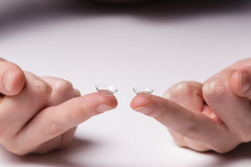 Girl holds a contact lens on  fingers