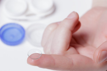 Girl holds a contact lens on the index finger