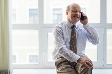 elderly businessman conducts informal talks on the phone