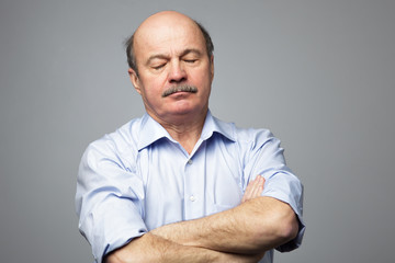 Elderly man falls asleep on standing with his arms crossed on his chest. Drowsiness from fatigue at work