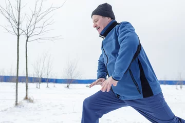 Foto auf Acrylglas Wintersport Man warming up before running in the winter on snow  © Viktor Koldunov