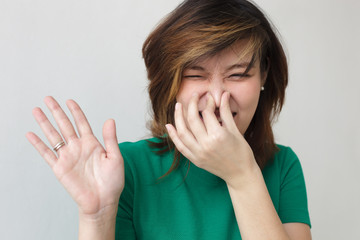 Japanese girl closes the nose with her hands. Unpleasant smell or stink