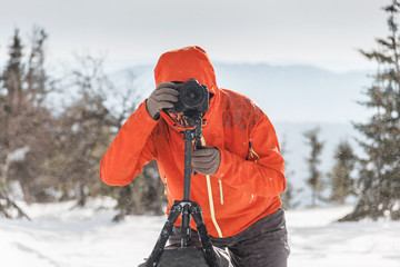 Photographer working with tripod in winter forest during trek