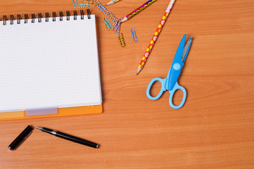 Top view of office tools with blank notebook on wooden table