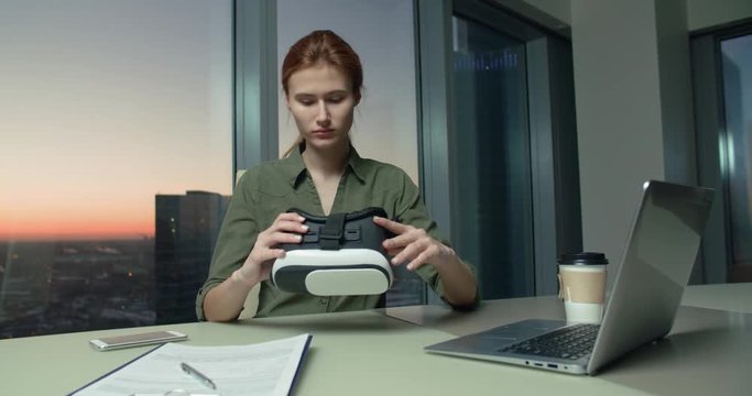 Technology VR-businessman young girl wears and uses virtual reality technology VR Glasses to work in modern office in a skyscraper. the creation of the presentation