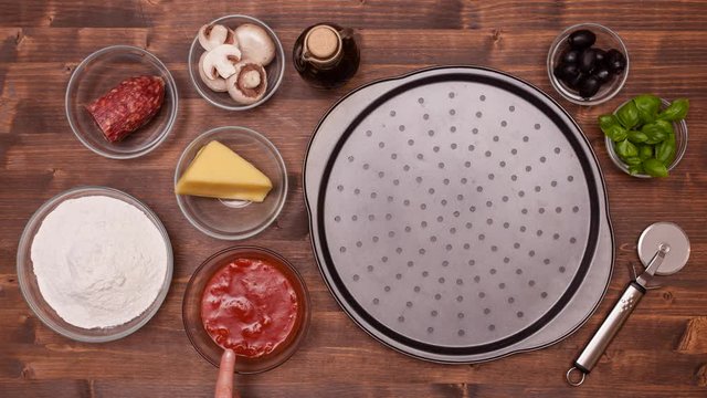Top view of making a pizza with ingredients transforming from a touch, on dark wooden table - stop motion animation, 4k