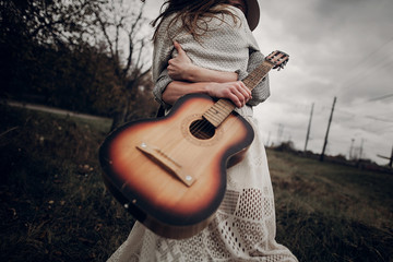 Hipster musician couple hugging in field, handsome man embracing gypsy woman in white dress, guitar...