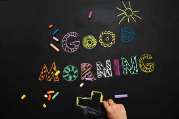 good morning. the kid draws on a black slate background.