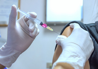 Close-up hands,nurses are vaccinations to patients using the syringe.Doctor vaccinating women in...