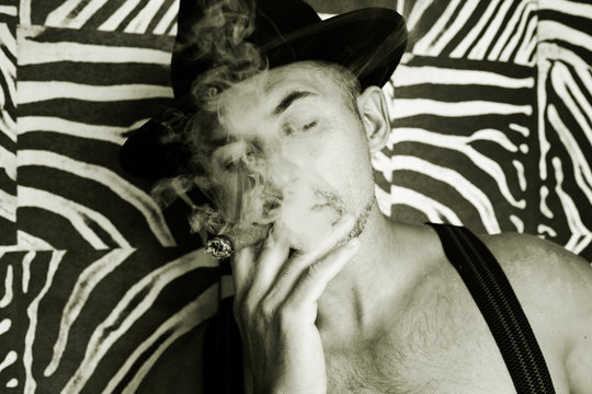 Macho in a felt hat and a cigar in the hands of a photo made in black and white