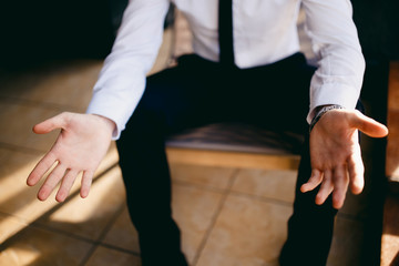 Obraz na płótnie Canvas Palms of hands close-up. Confident businessman man in white shirt and black tie. Dark background