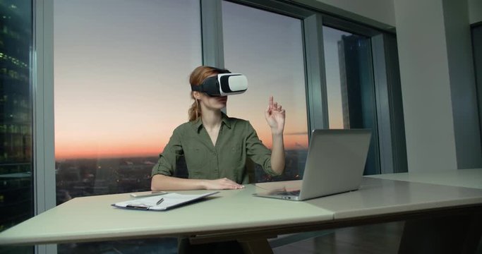 Technology VR-businessman young girl wearing virtual reality technology VR Glasses to work in modern office in a skyscraper. the creation of the presentation
