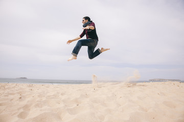 young man jumping high on the sand isolated on the beach