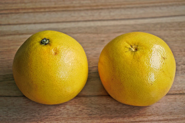 Two yellow grapefruits on a wooden table