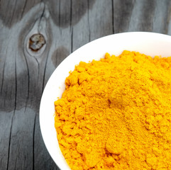 Turmeric powder in white cup on wooden floor.