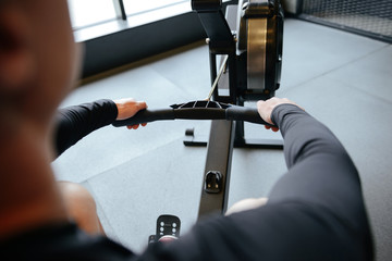 Back view of Muscular man using rowing machine