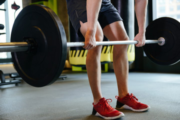 Fototapeta na wymiar Cropped image of Athletic man doing exercise with barbell