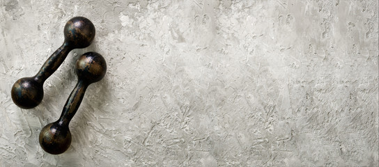 Old dumbbells on concrete background. Sport concept. Free space for your text.