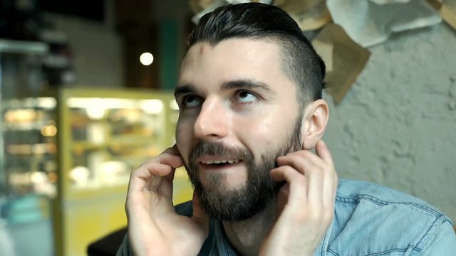 Handsome man with mun bun telling someone a story in the cafe
