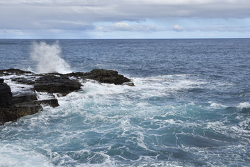Waves against a cliff with blue sea in background