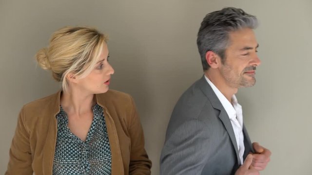 Middle-aged couple standing on grey background, isolated