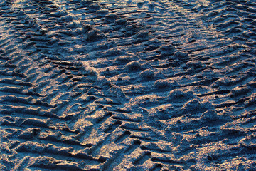 Tire traces and caterpillar tread marks on sandy ground