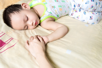 Obraz na płótnie Canvas Asian mother holding baby hand while sleeping