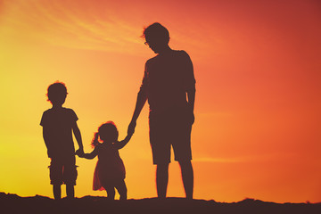 father with little son and daughter walking at sunset