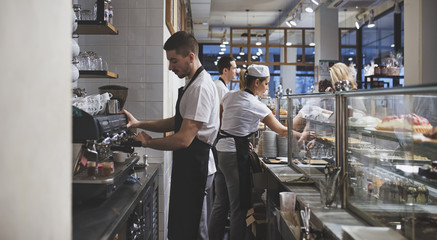 Bartenders and bakers working together at coffee and pastry shop.