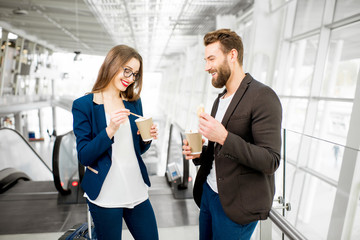 Business couple waiting with coffee to go at the airport. Business travel concept