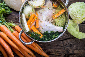 Top view of chicken soup -  broth on wooden table with vegetable.