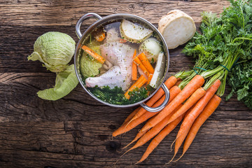 Top view of chicken soup -  broth on wooden table with vegetable. - obrazy, fototapety, plakaty