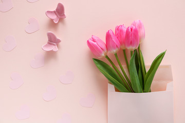 Obraz na płótnie Canvas Pink tulip flowers in an envelope on pink background. 