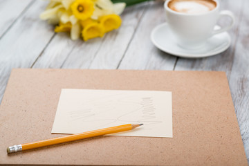  cup of coffee next to spring white flowers on wooden texture