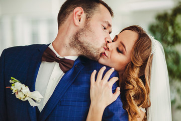 Groom kisses bride while she hugs him from behind
