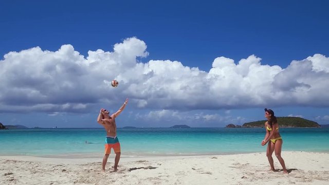 young couple playing volleyball on a tropical beach in the Caribbean
