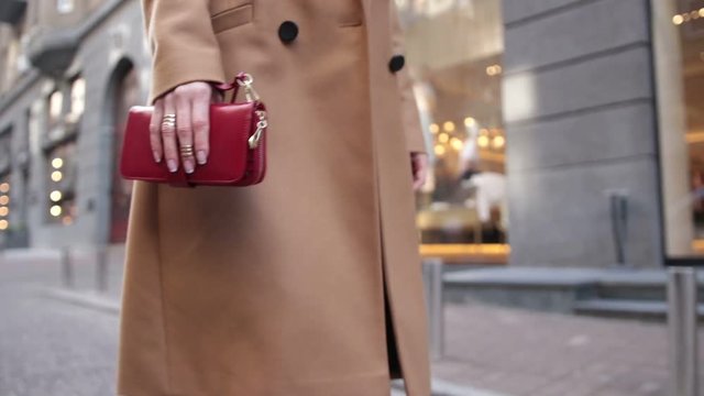 Woman holding red clutch while walking on street