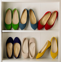Rows of colorful women's shoes (ballet shoes) in the wardrobe.