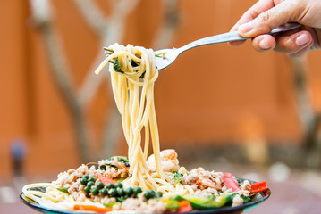 Drunken noodles seafood spaghetti in gray dish on wooden table.